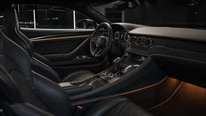 Interior de hyper GT con cuero negro, fibra de carbono, iluminación ambiental y puesto de conducción deportivo.