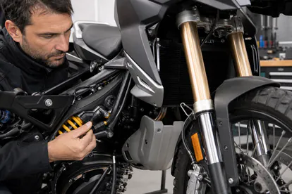 Mecánico inspecciona horquilla y amortiguador de una moto trail moderna