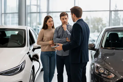 Pareja comparando un deportivo eléctrico y otro de combustión en una exposición.