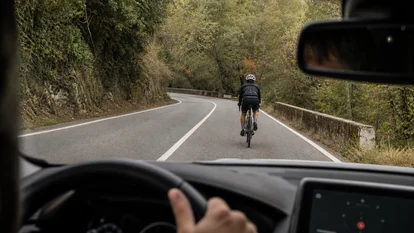 Conductor esperando detrás de un ciclista en una curva sin visibilidad suficiente.